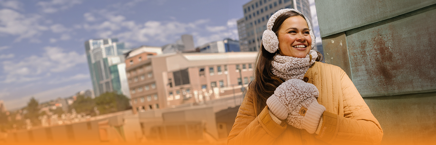 header image of a woman wearing earmuffs and mittens with a city backdrop